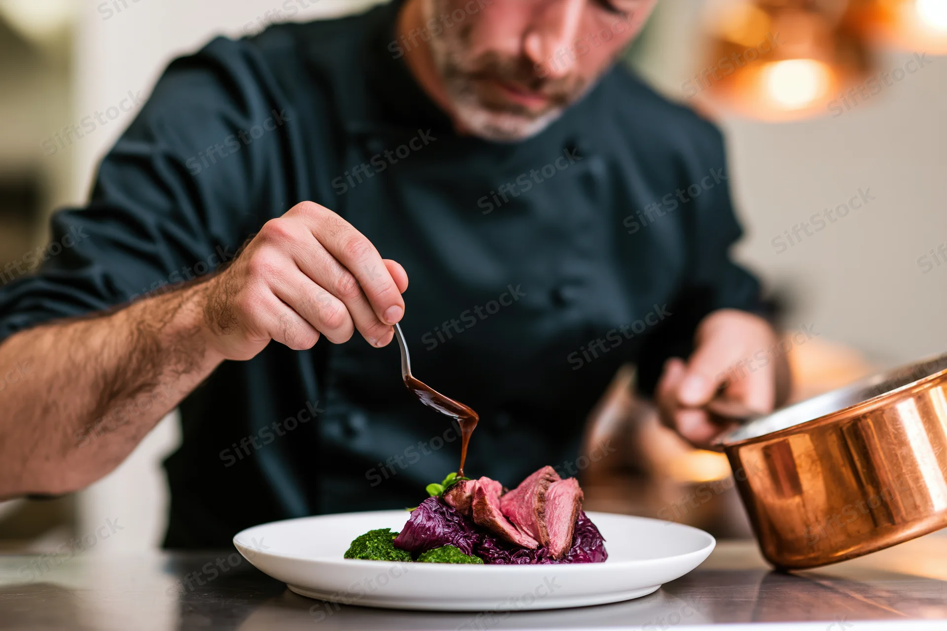 Chef plating sliced red meat with sauce on a white plate in a restaurant kitchen