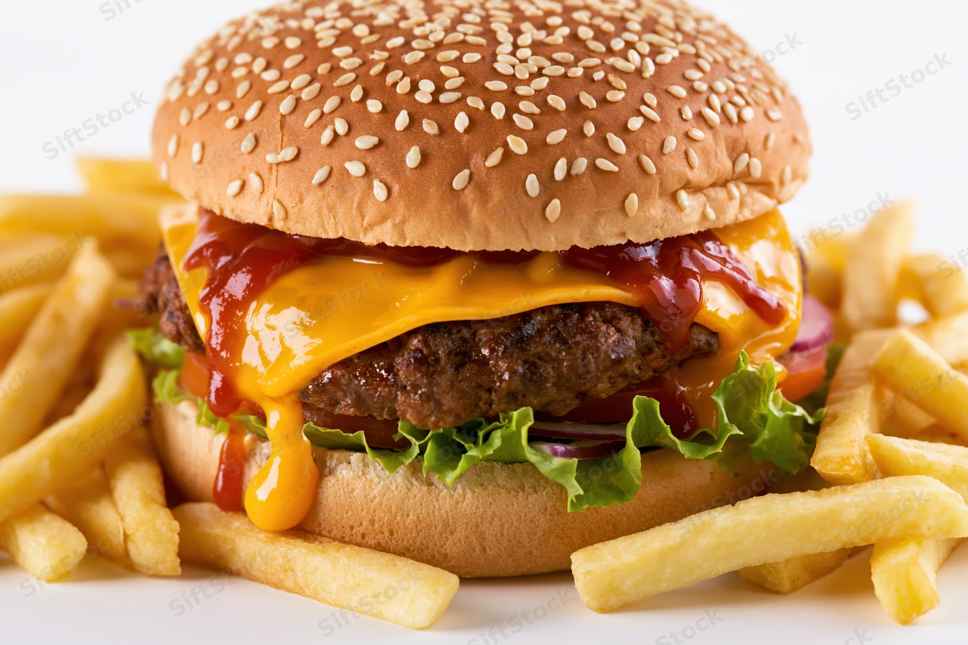 Cheeseburger with sesame seed bun, thick beef patty, melted cheese, ketchup, lettuce and red onion, served with french fries on white background