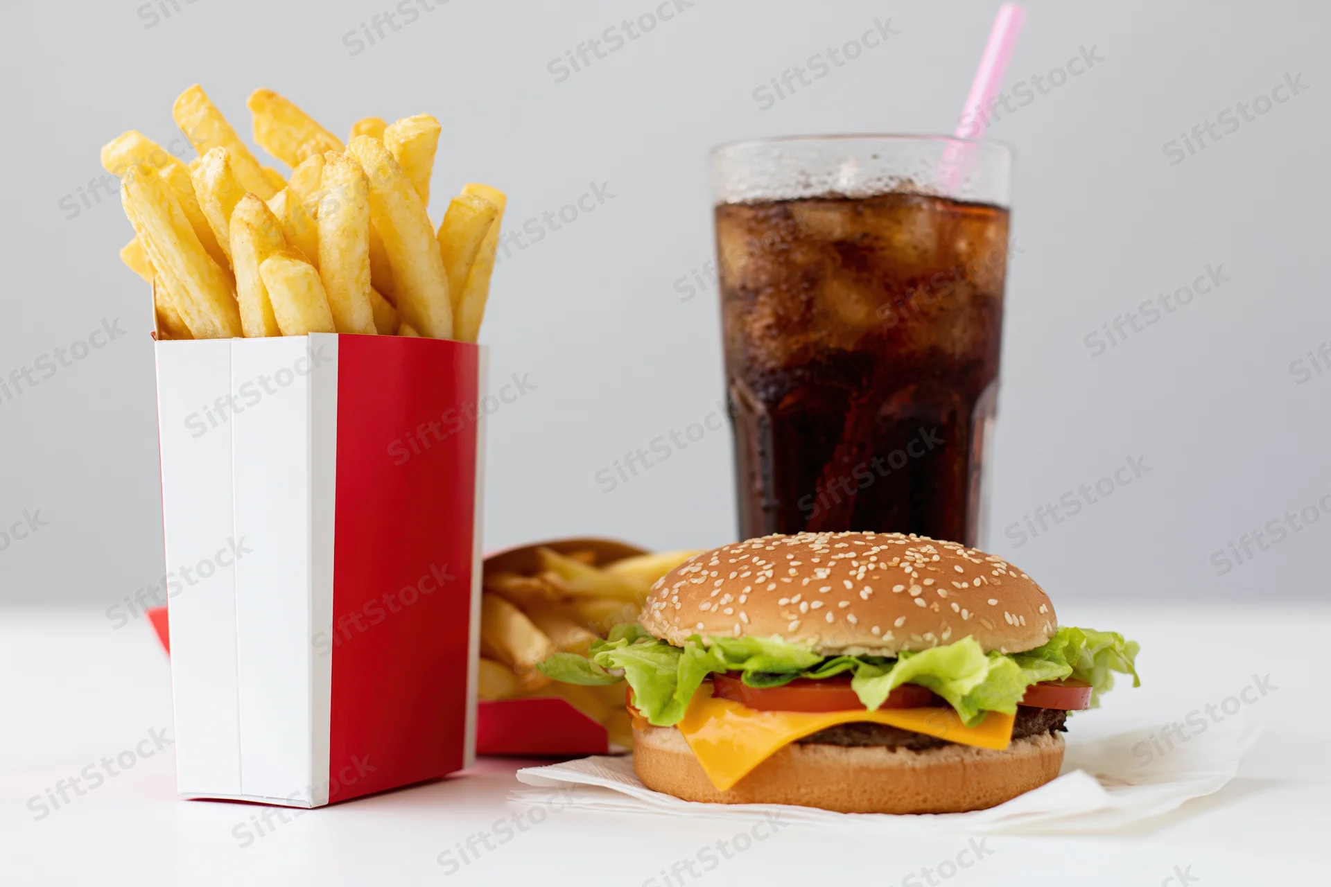 Hamburger with fries and soda arranged on a white surface