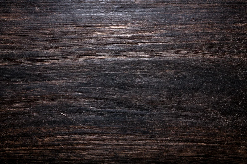 Close-up of dark aged wooden surface with worn grain pattern