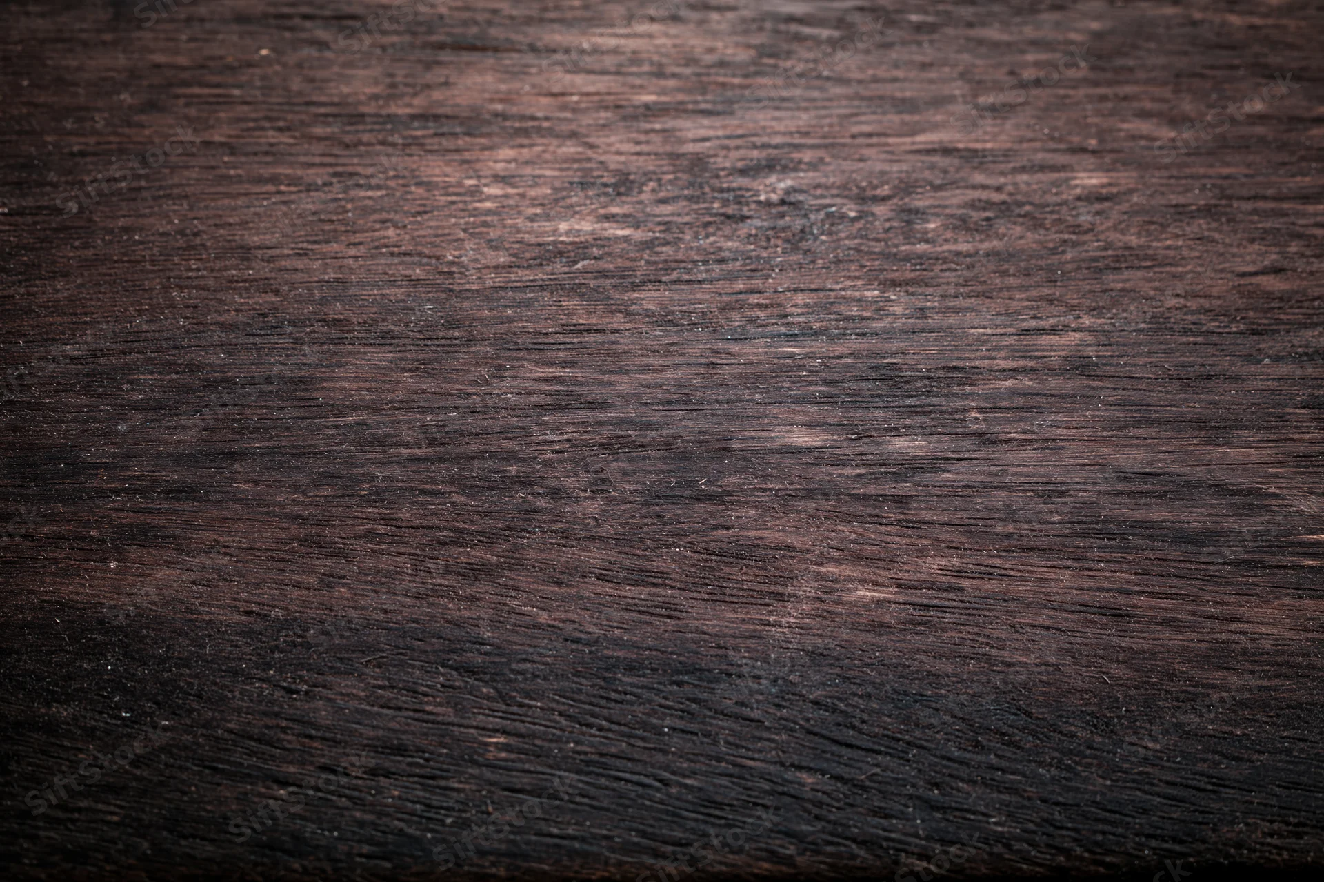 Close-up of dark aged wooden surface with worn grain pattern