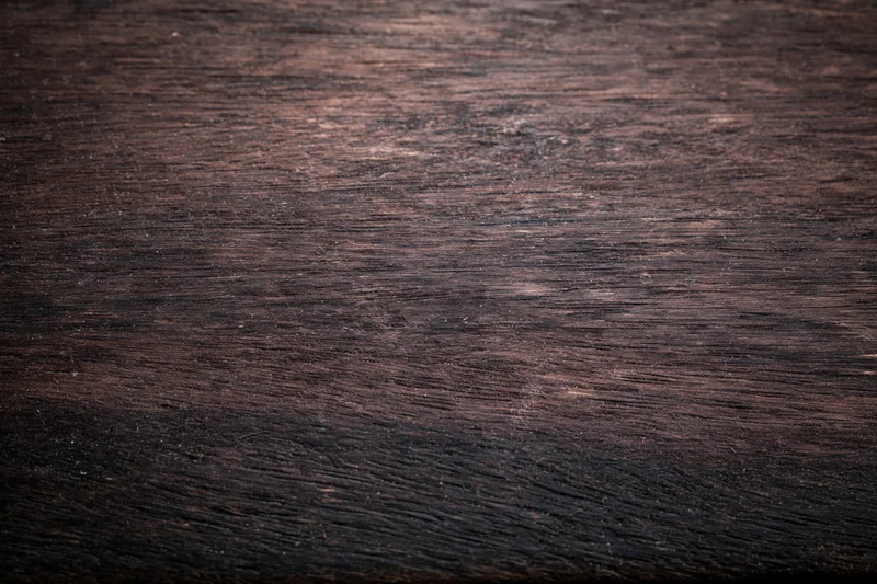 Close-up of dark aged wooden surface with worn grain pattern