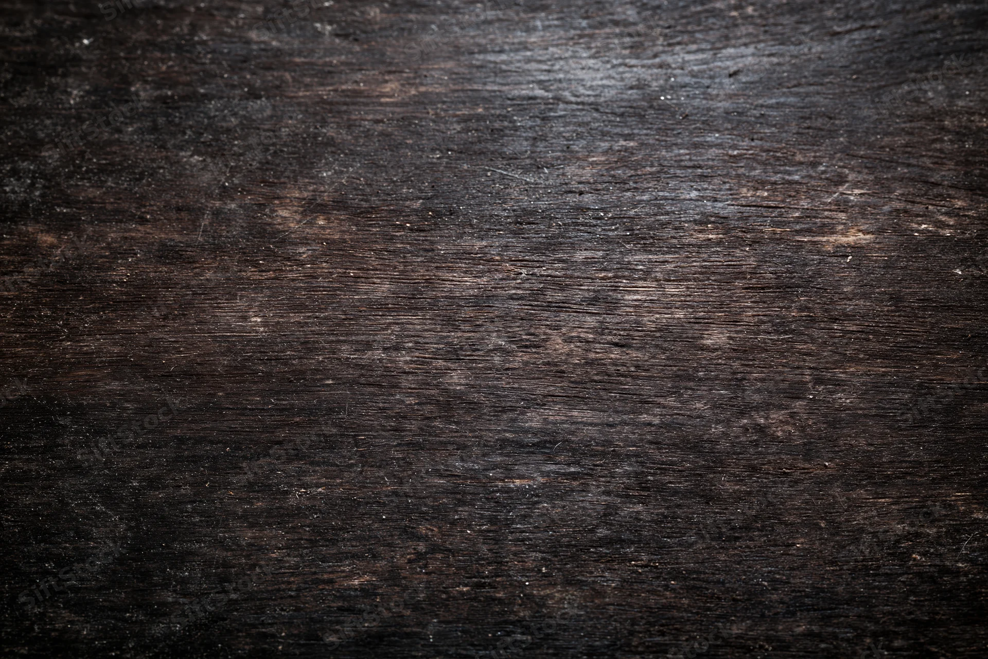Close-up of a dark aged wooden surface with worn grain and rustic texture