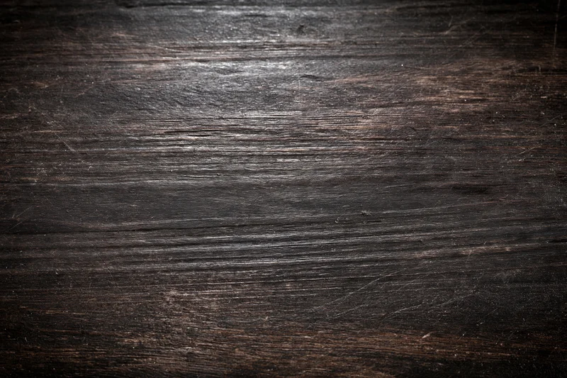 Close-up of dark aged wooden surface with worn grain pattern