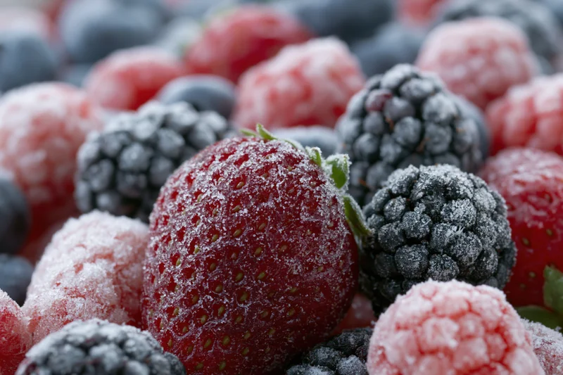 Close-up of mixed frozen berries covered in frost, including strawberries, raspberries, blackberries and blueberries