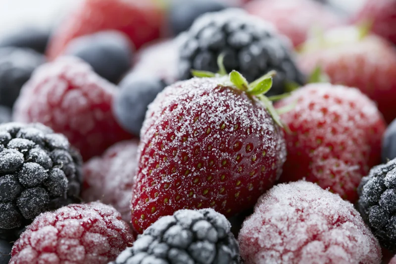 Close-up of mixed frozen berries covered in frost, including strawberries, blackberries, raspberries and blueberries