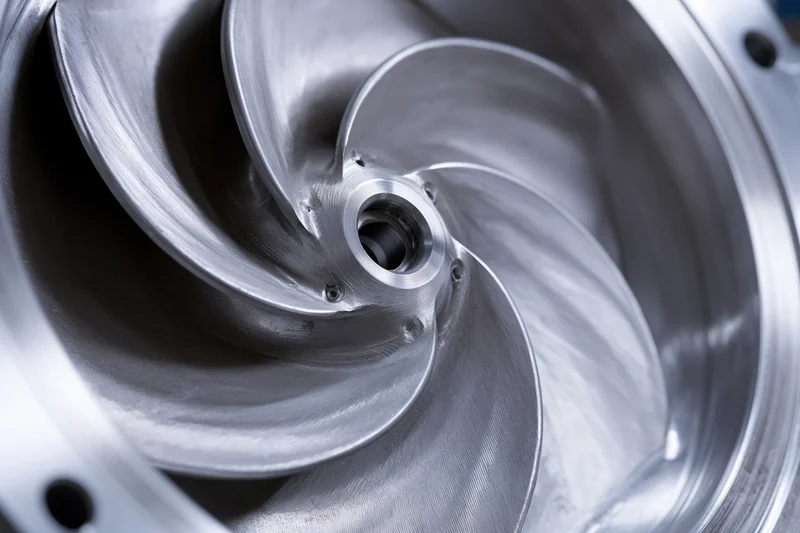 Close-up of a precision-machined metal impeller with curved blades inside a mechanical component