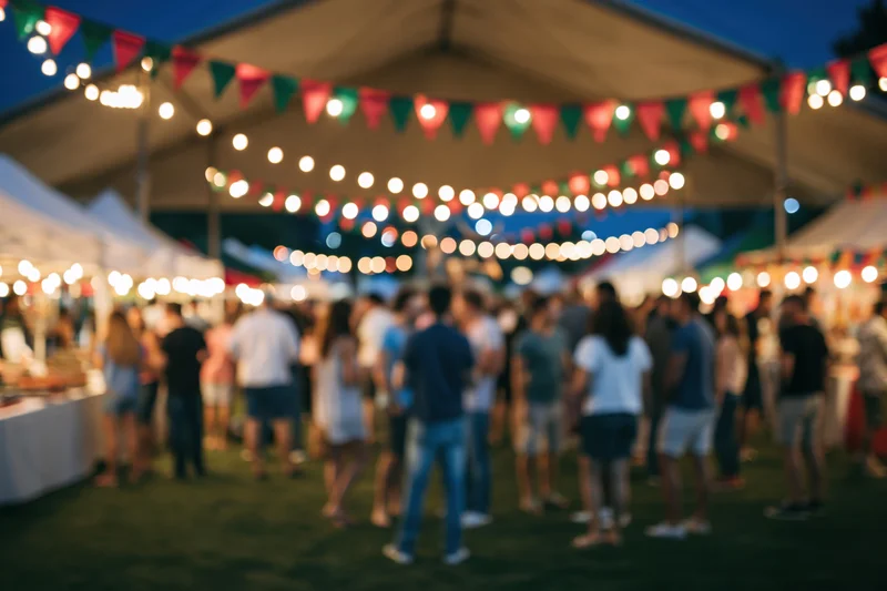 Crowd of people milling around an outdoor night market under string lights and tents