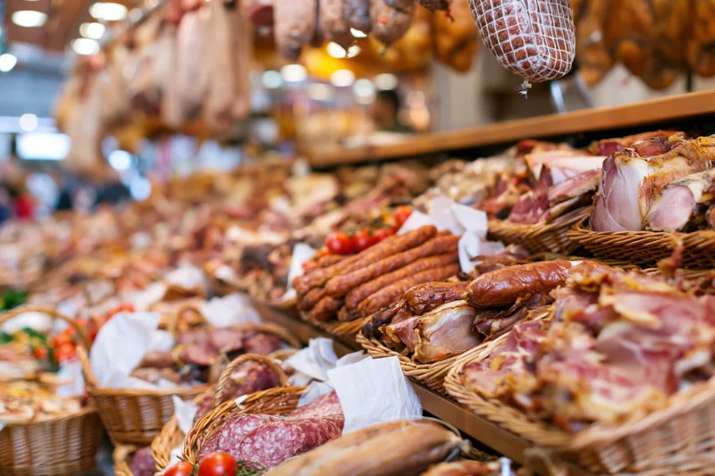 Cured meats arranged in wicker baskets on a deli market stall display