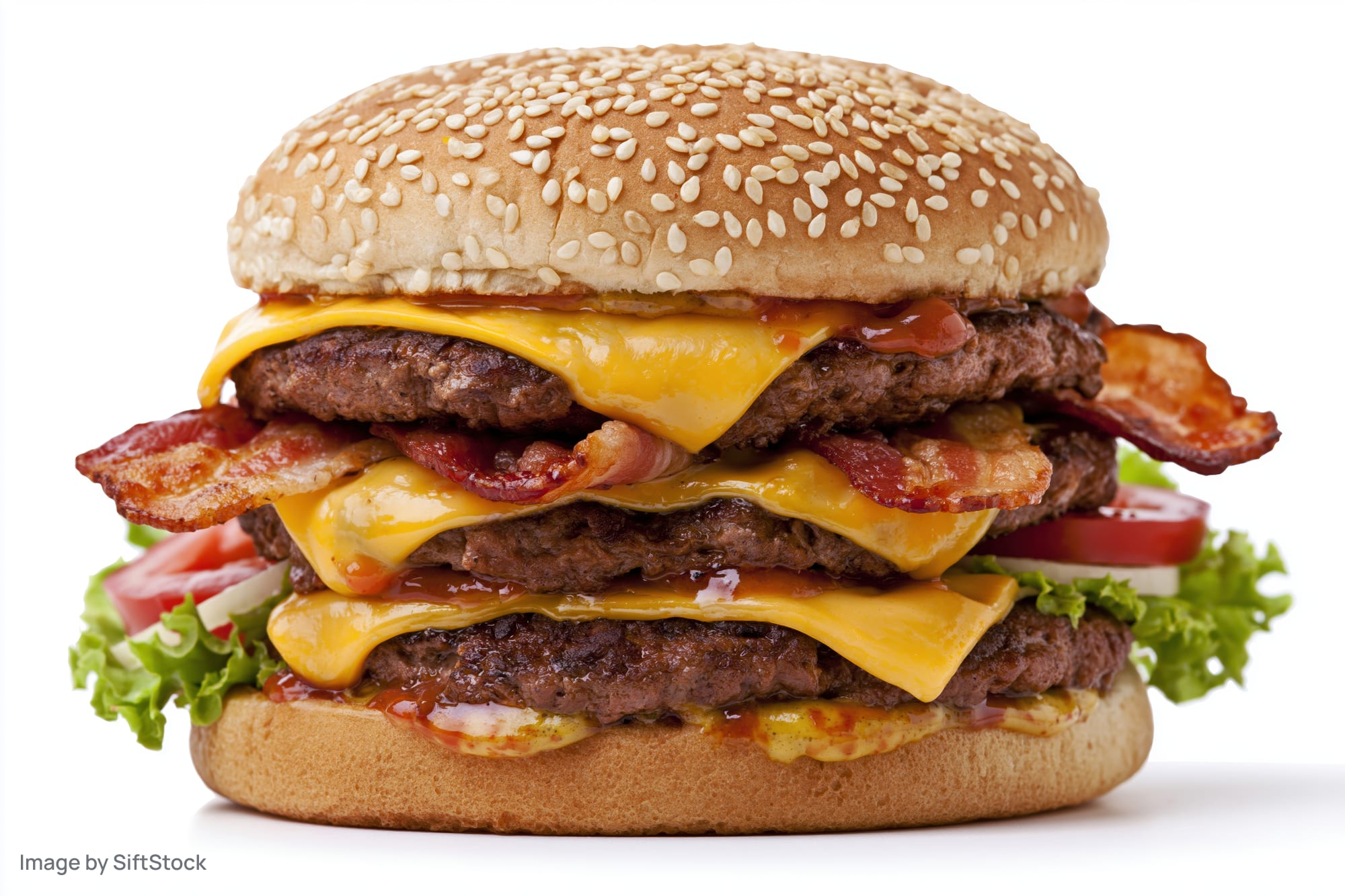 Double cheeseburger with two beef patties, melted cheese, bacon, lettuce, tomato, and onion on a sesame seed bun, isolated on white background