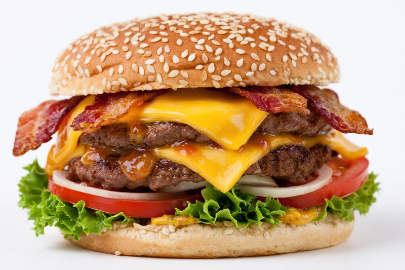 Double cheeseburger with two beef patties, melted cheese, bacon, lettuce, tomato, and onion on a sesame seed bun, isolated on white background