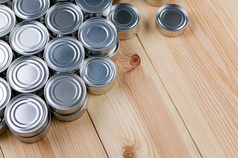 Silver tin cans stacked together on a wooden surface