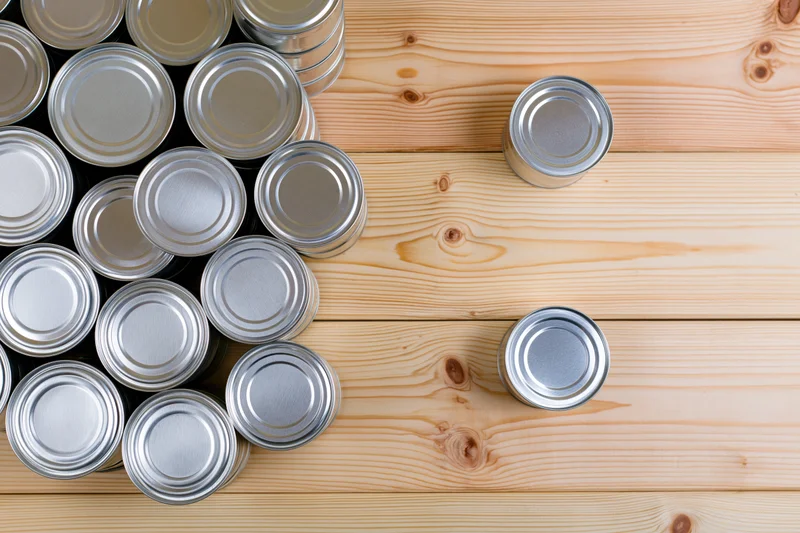 Silver tin cans grouped on wooden surface with copyspace on right