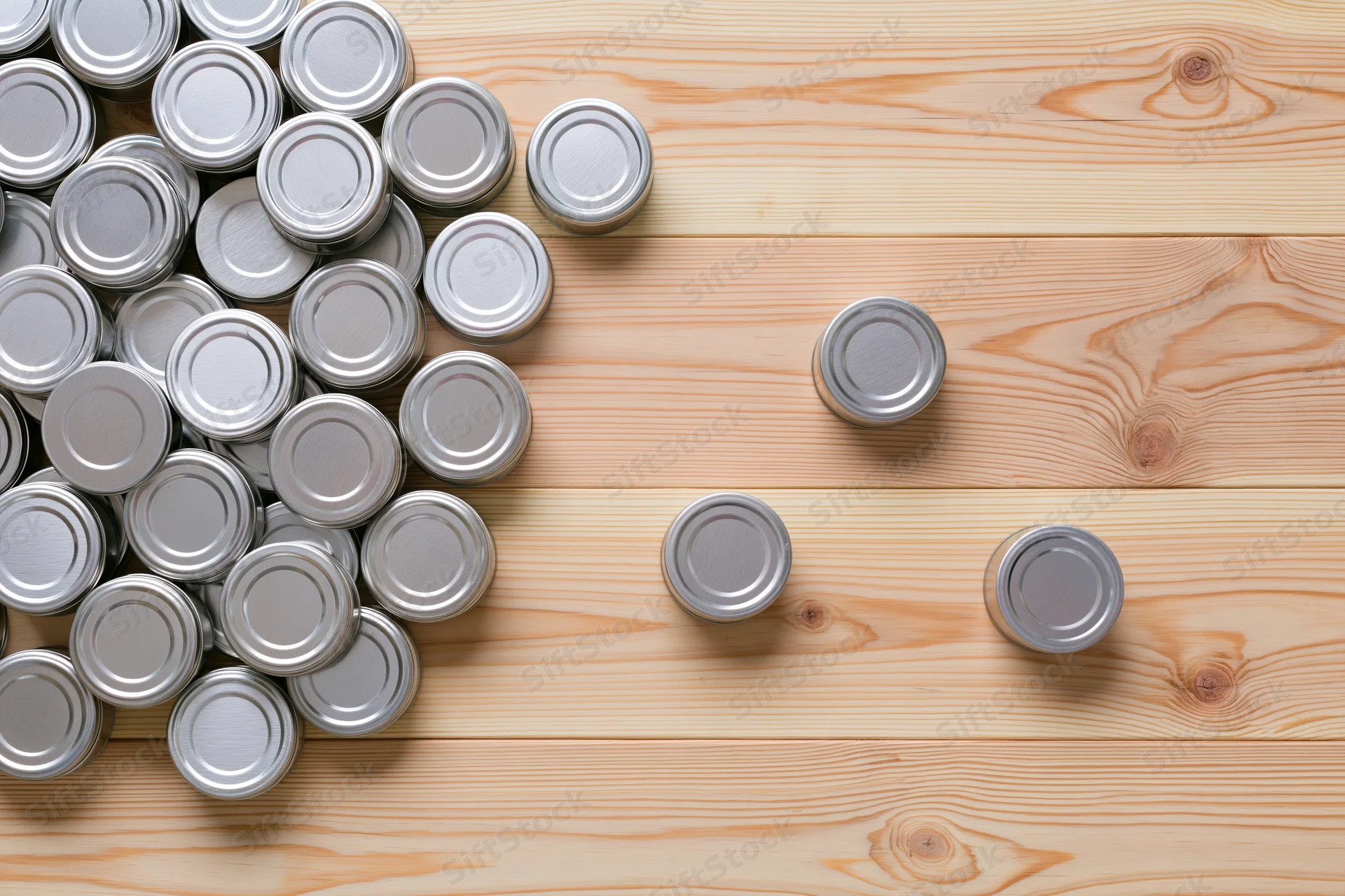 Silver tin cans grouped on wooden surface with copyspace
