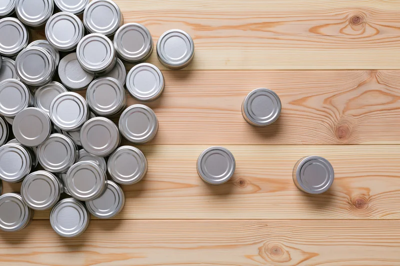 Silver tin cans grouped on wooden surface with copyspace