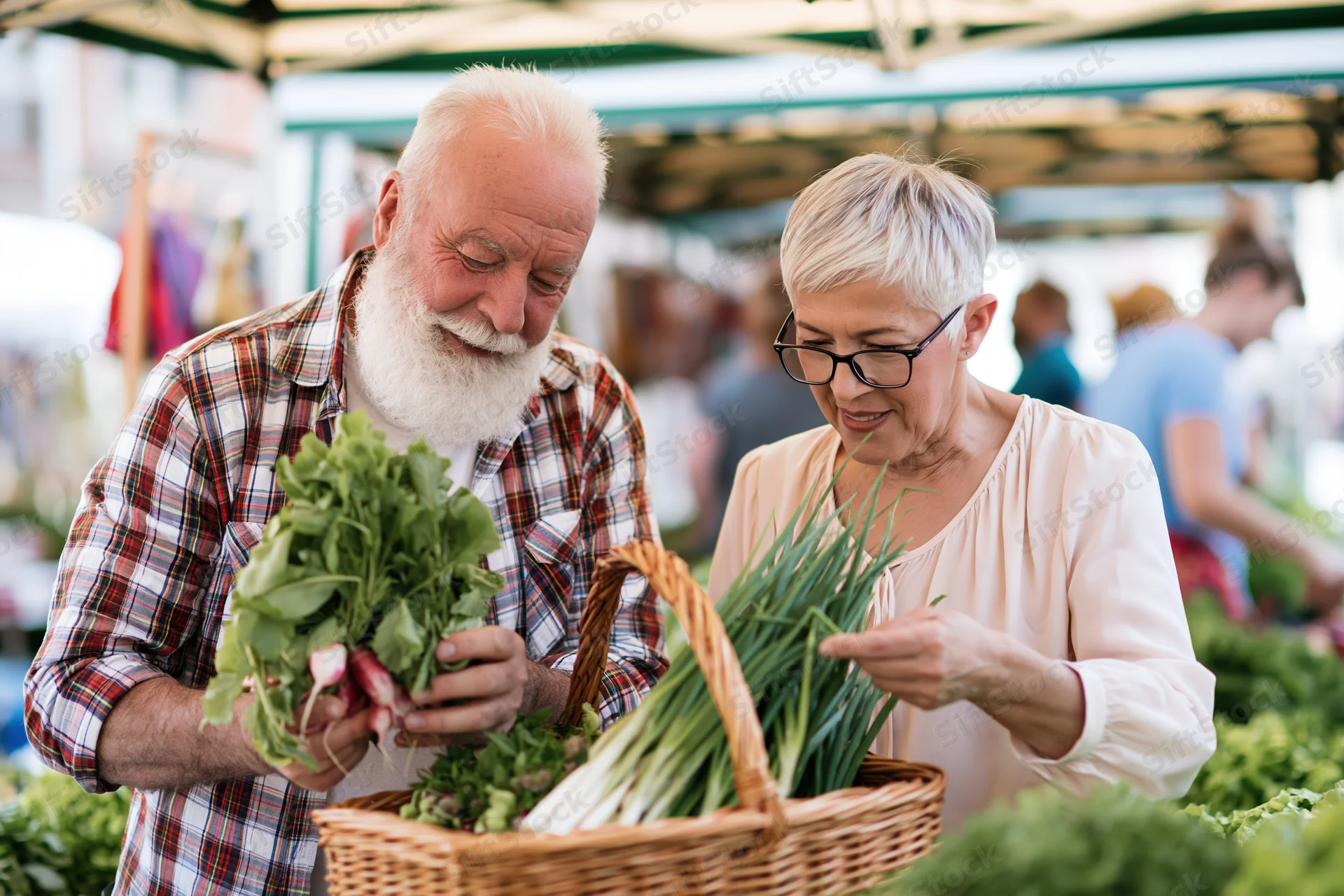 Elderly couple selecting fresh vegetables at outdoor market