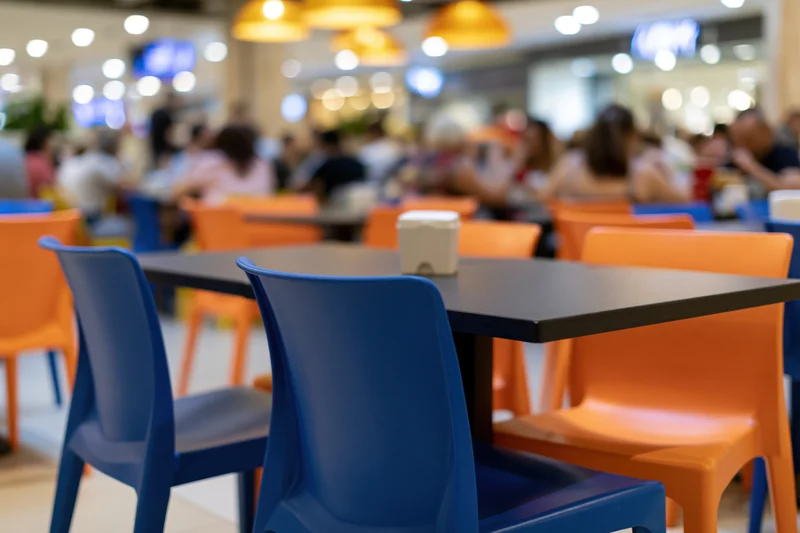 Empty tables and chairs in a food court seating area inside a shopping mall