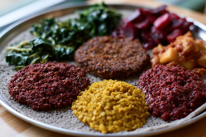 Ethiopian injera platter with stews and vegetables served on a round metal tray