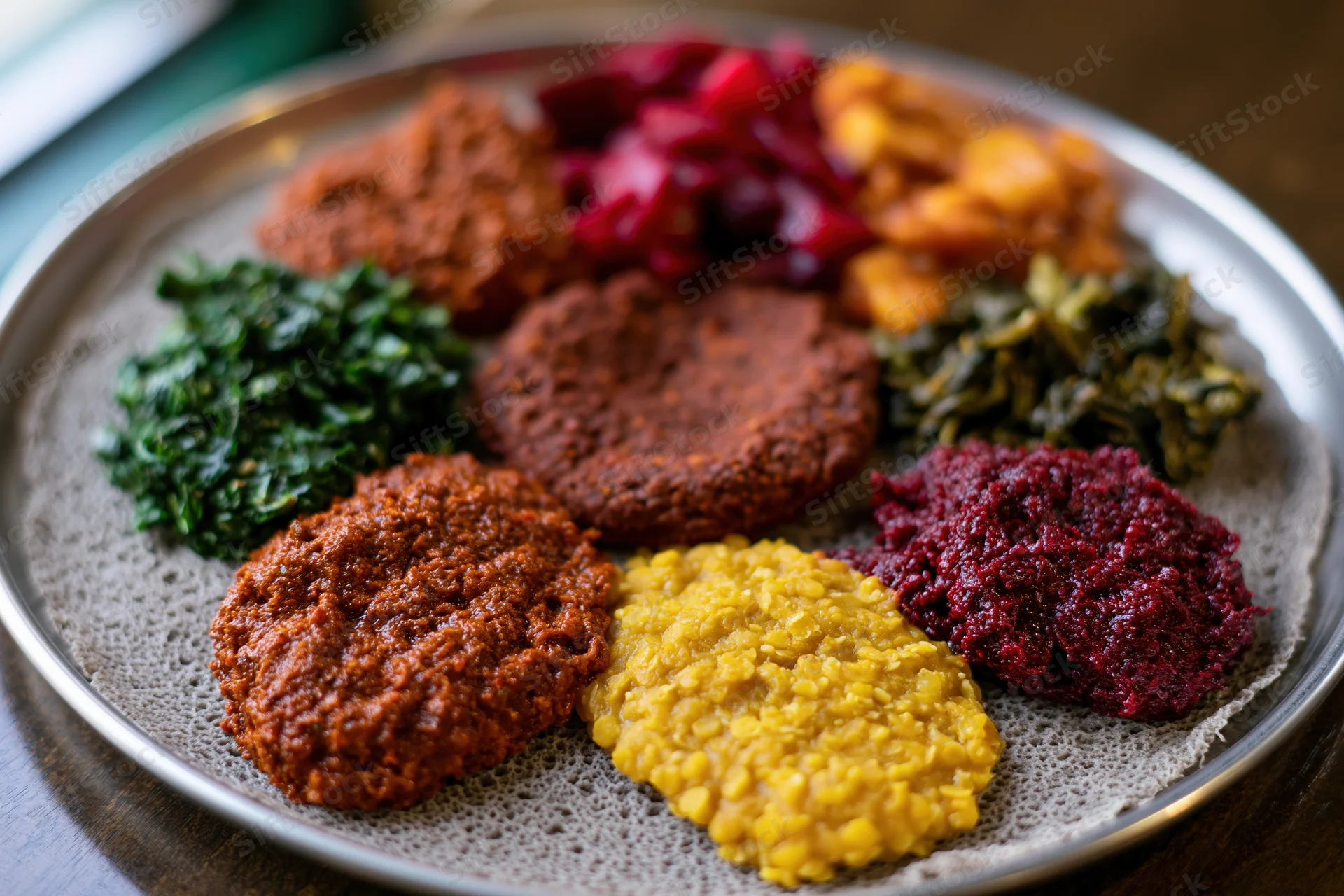Ethiopian injera platter with various stews and vegetables served on a round metal tray