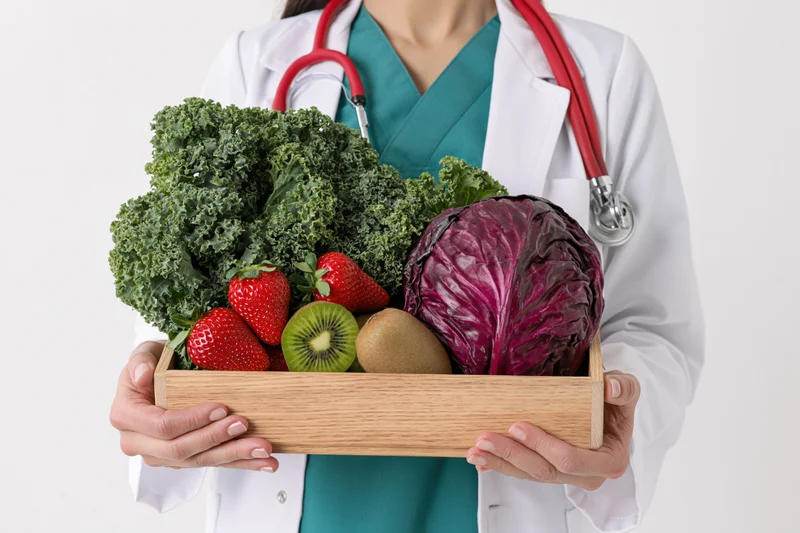 Female doctor holding wooden tray with fresh vegetables and fruit