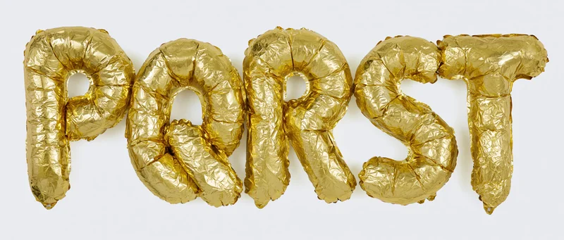 Gold mylar foil balloons spelling p q r s t arranged in a row on a white background