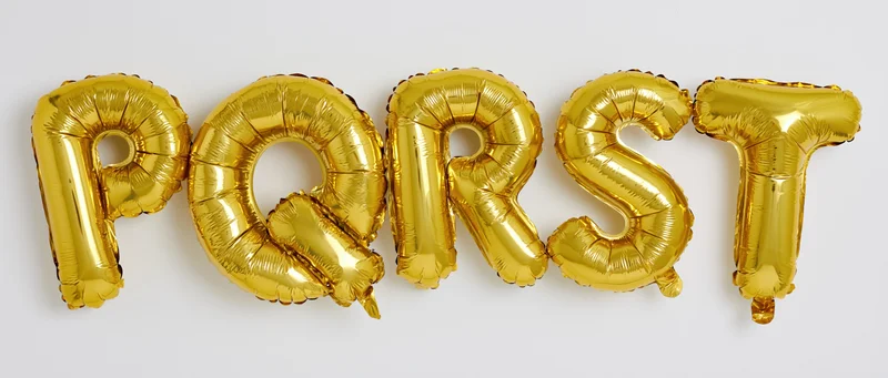 Gold mylar letter balloons spelling p q r s t arranged horizontally on white background