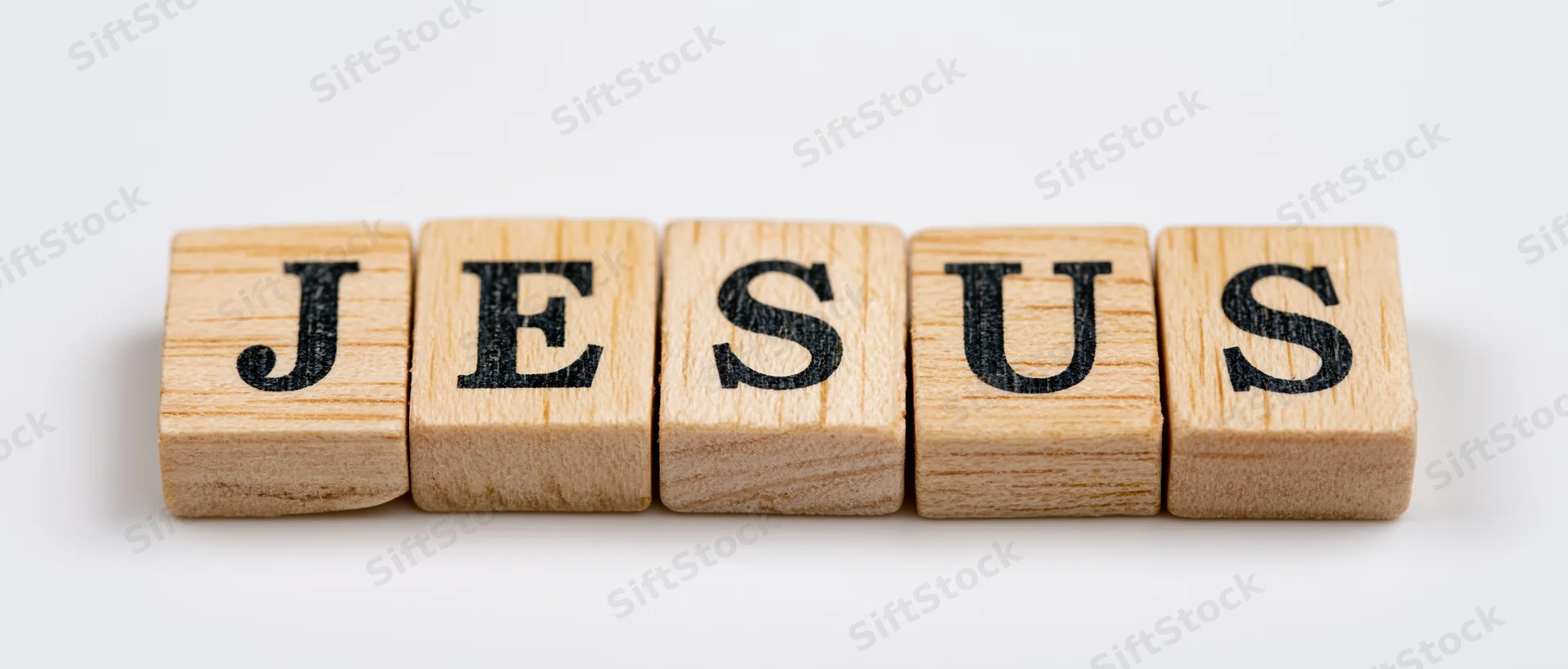 Wooden letter tiles spelling jesus in a row on white background