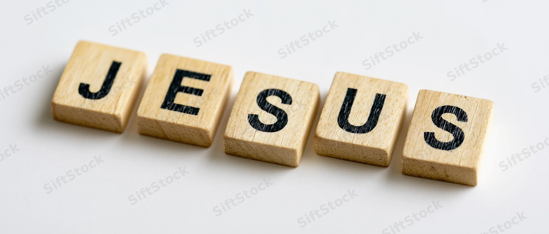 Wooden letter tiles spelling jesus arranged in a row on white background