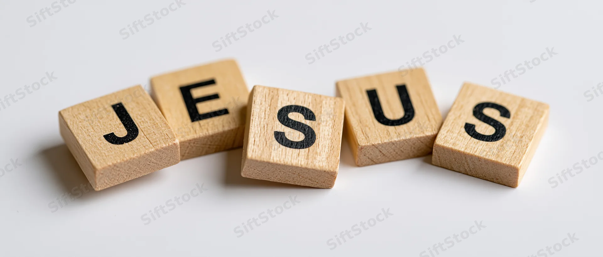 Wooden letter tiles spelling jesus arranged in a row on a white surface