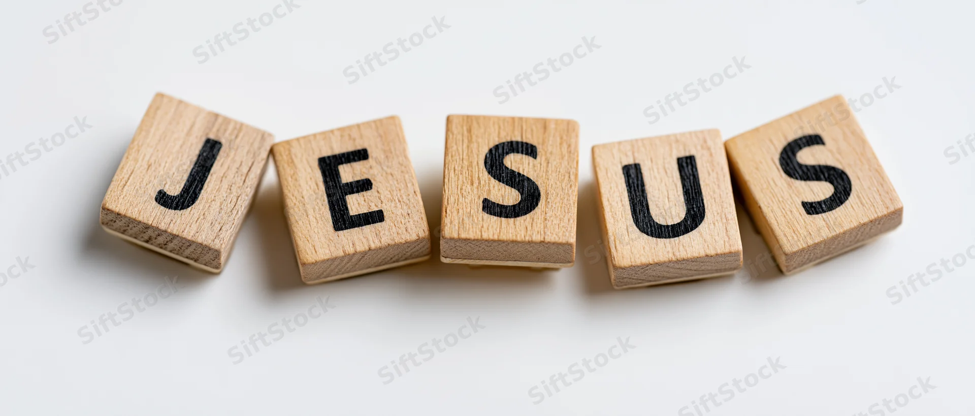 Wooden letter tiles spelling jesus arranged in a row on white background