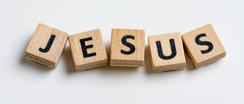 Wooden letter tiles spelling jesus arranged in a row on white background