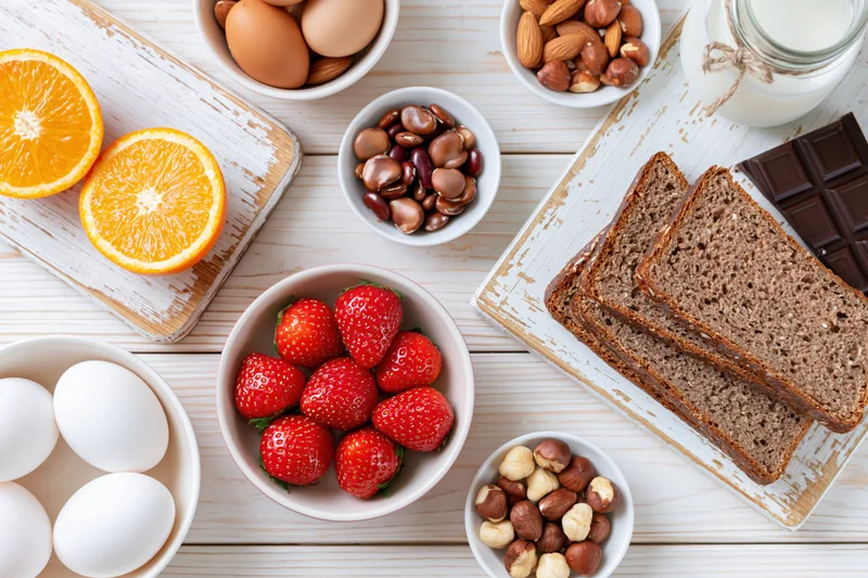Flat lay of common allergy foods arranged on a white wooden table