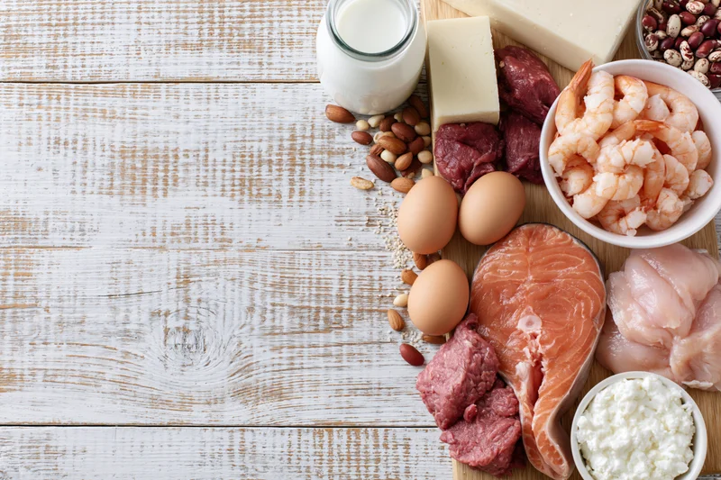 High-protein foods arranged on a whitewashed wooden table with copyspace on the left