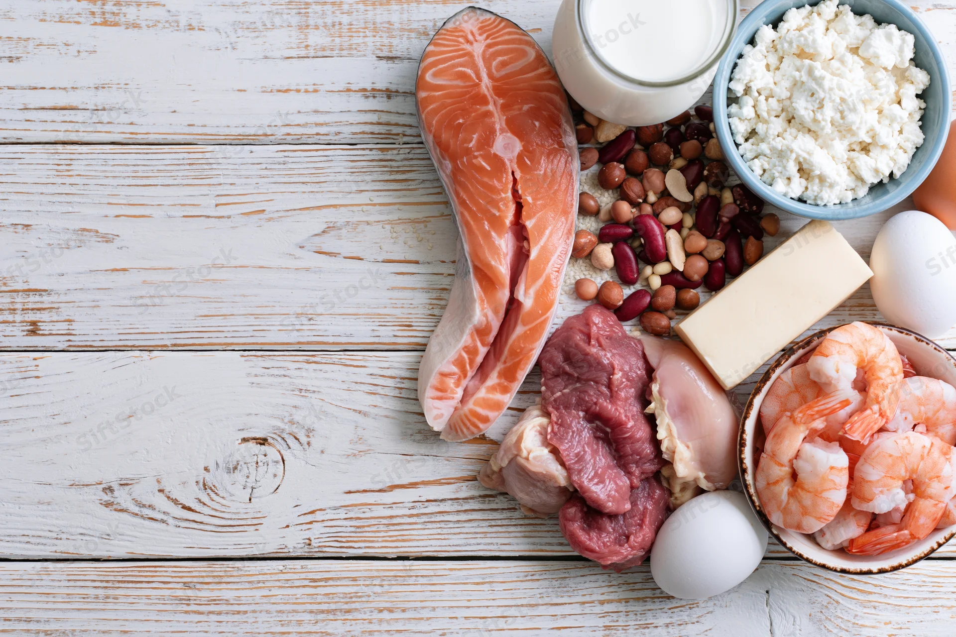 High-protein foods arranged on a whitewashed wooden table in flat lay view