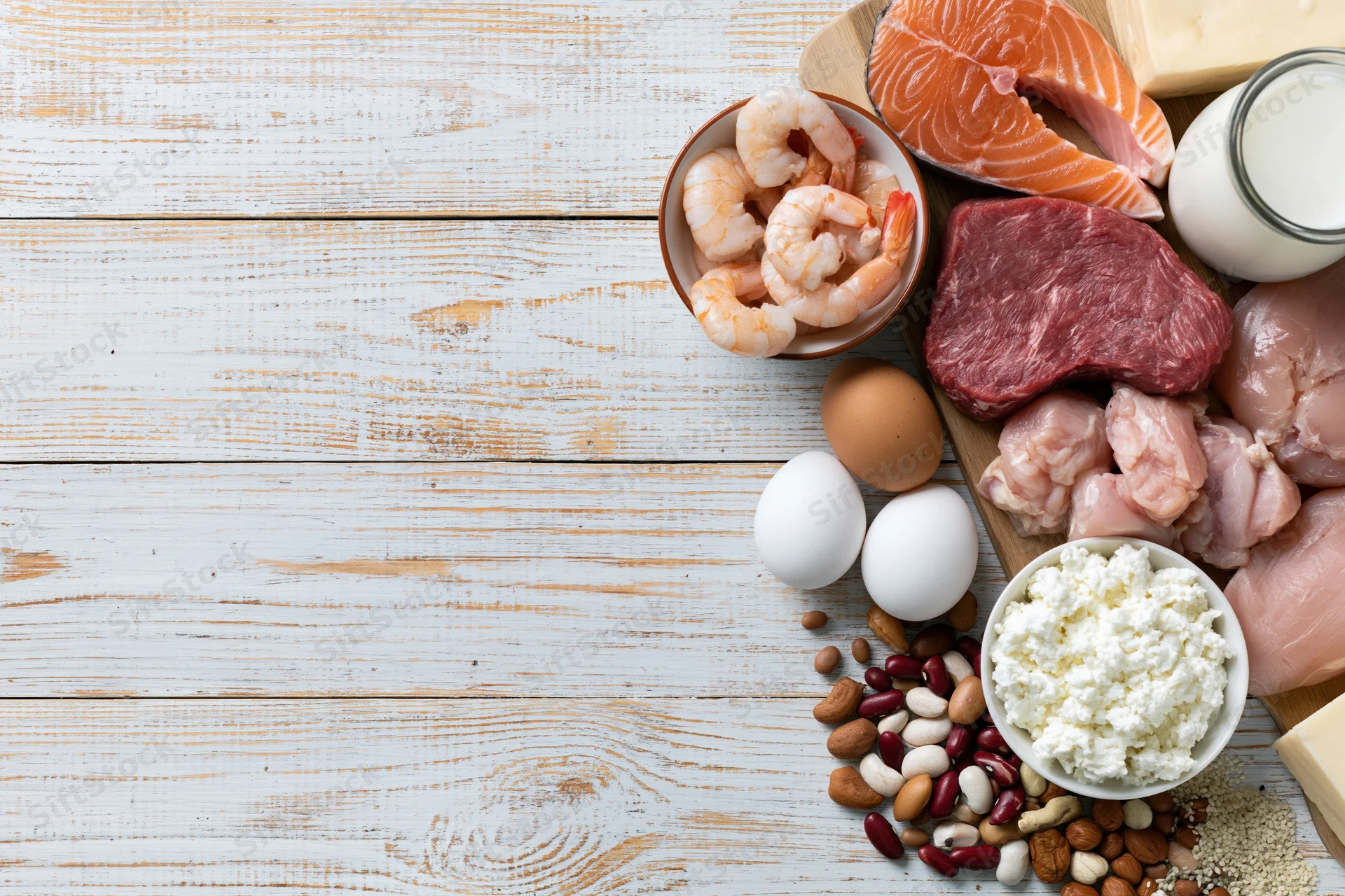 High-protein foods arranged on a whitewashed wooden table with copyspace on the left
