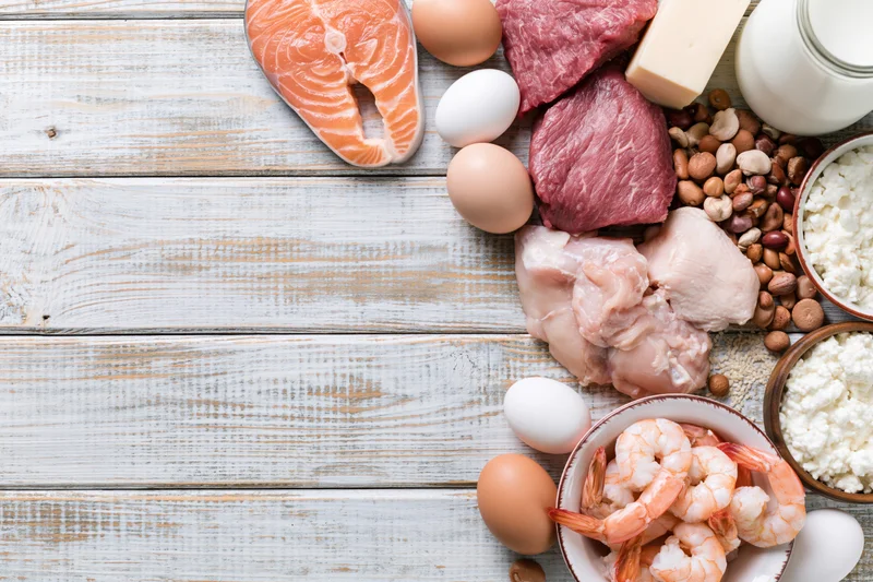 High-protein foods arranged on whitewashed wooden surface with copyspace