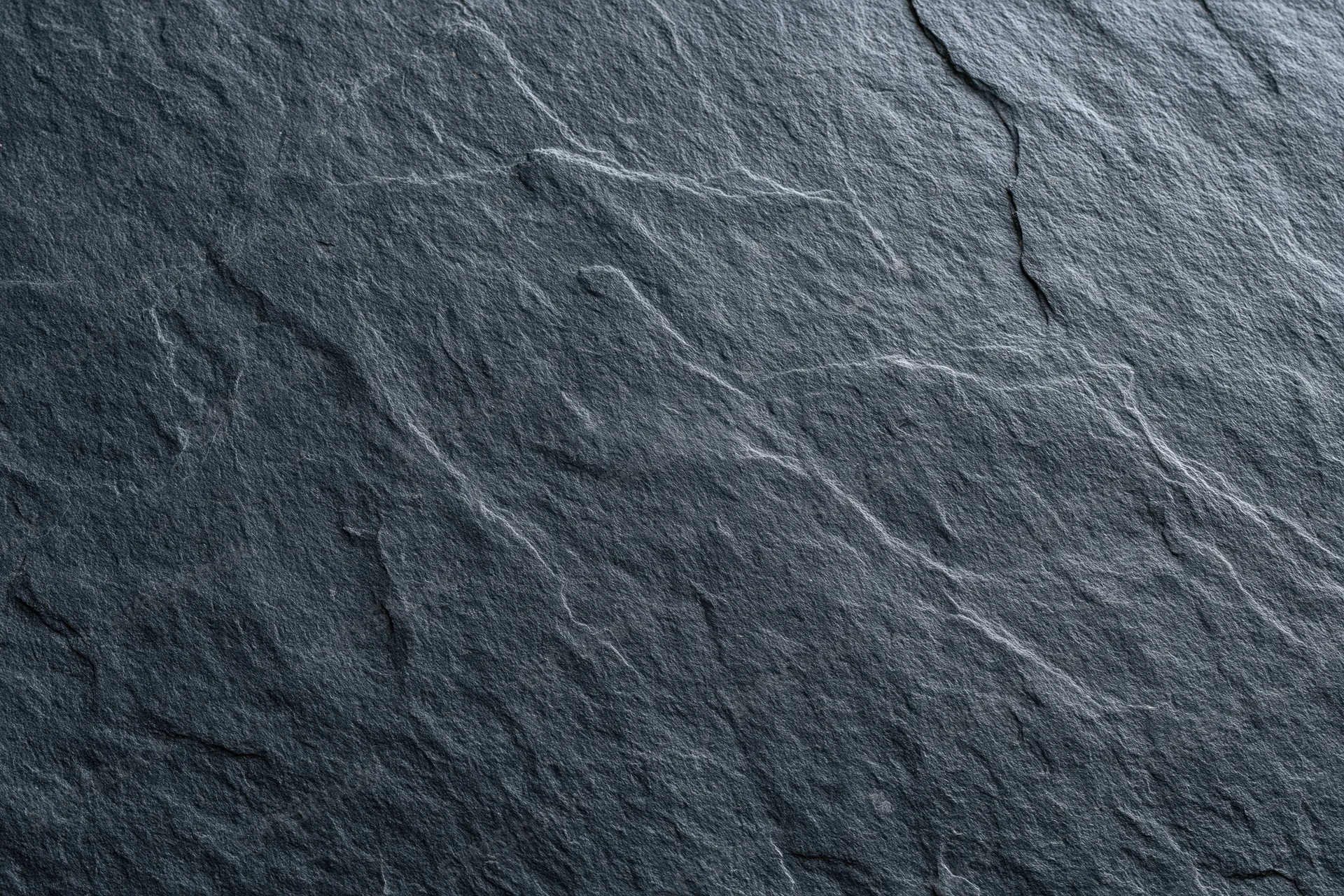 Close-up of dark slate stone surface with natural cracks and veins