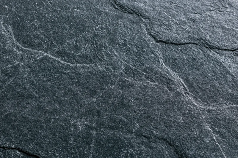Close-up of dark slate stone surface with natural cracks and veins