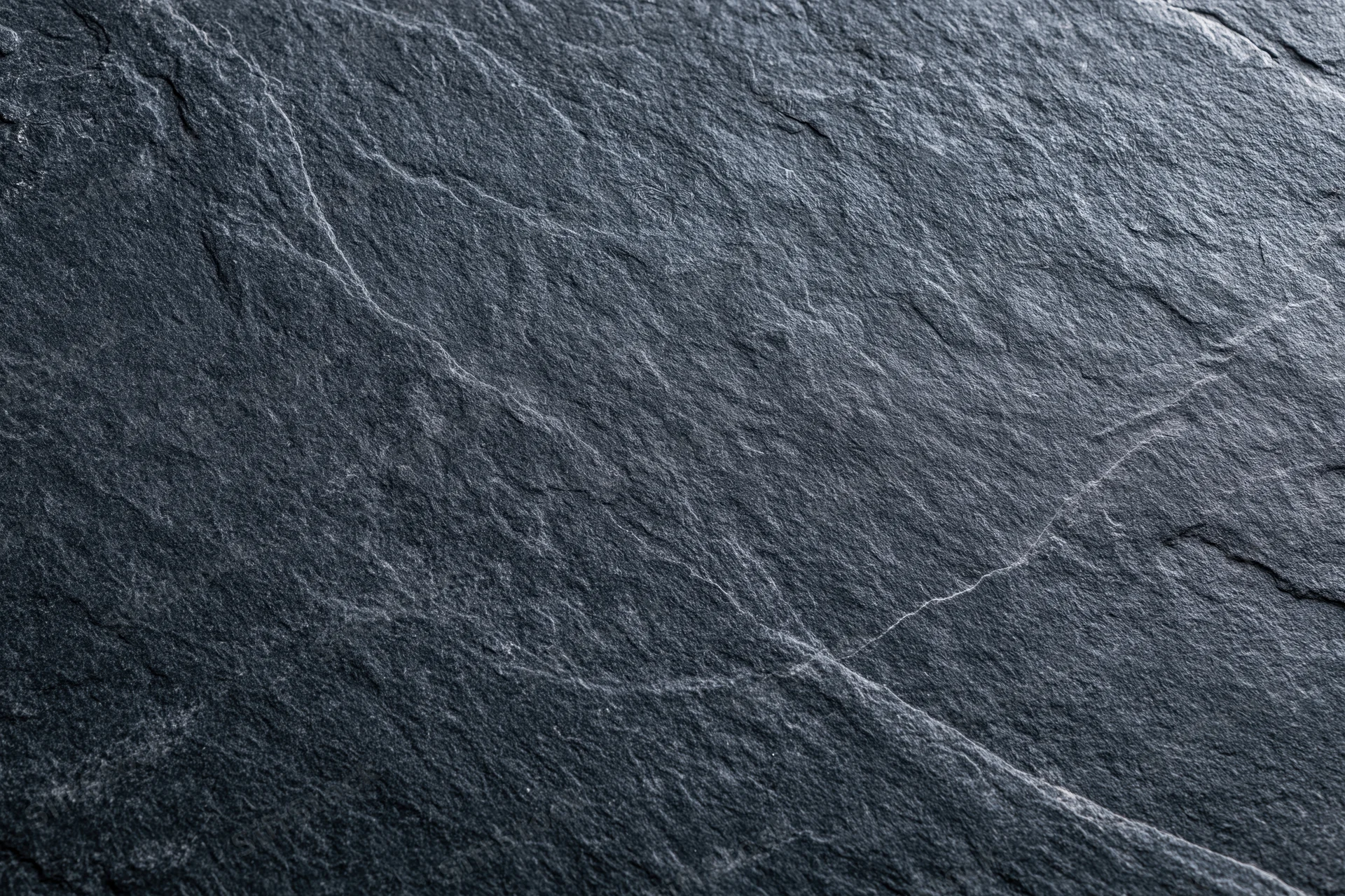 Close-up of dark slate stone surface with natural cracks and texture