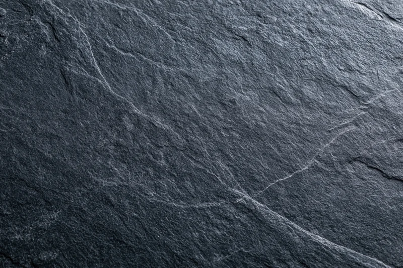 Close-up of dark slate stone surface with natural cracks and texture