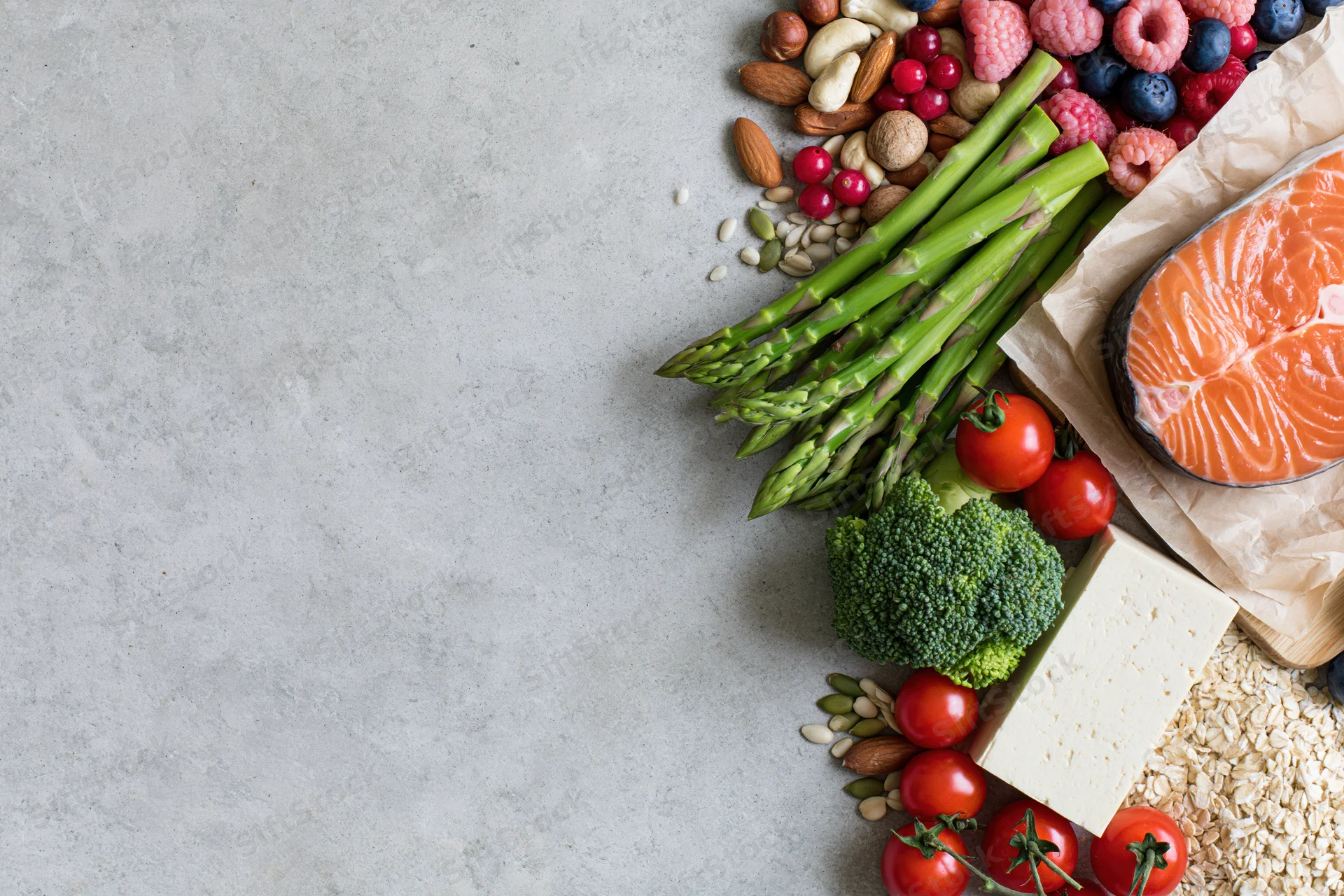 Fresh salmon and vegetables arranged along the right edge of a gray surface