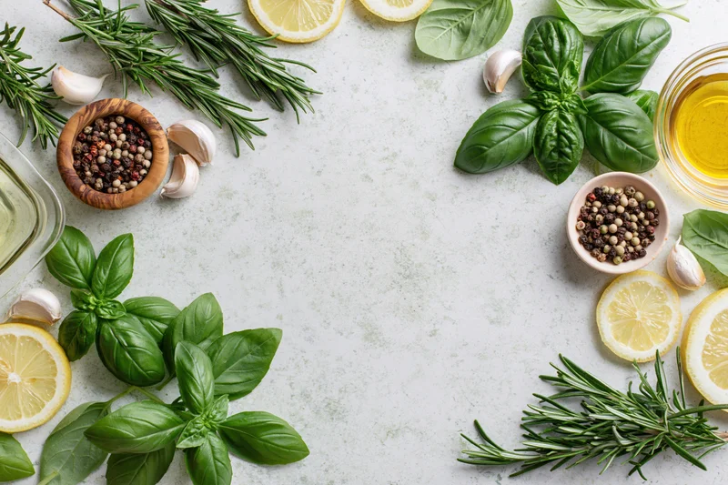 Fresh herbs and ingredients arranged in a flat lay on a marble surface with copyspace