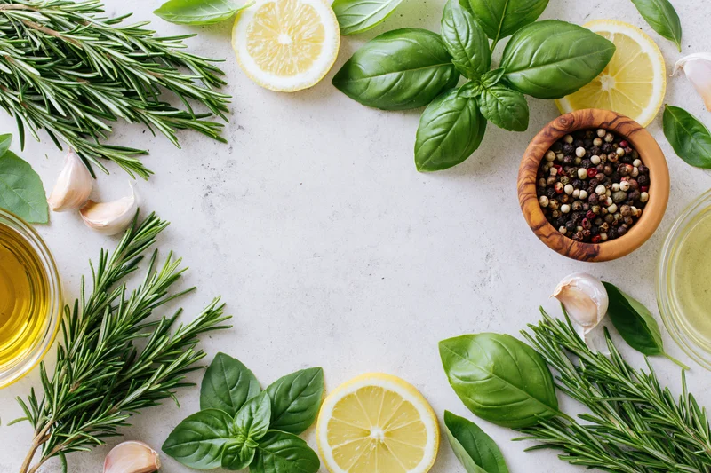 Fresh herbs and ingredients arranged in a flat lay on a white marble surface with copyspace