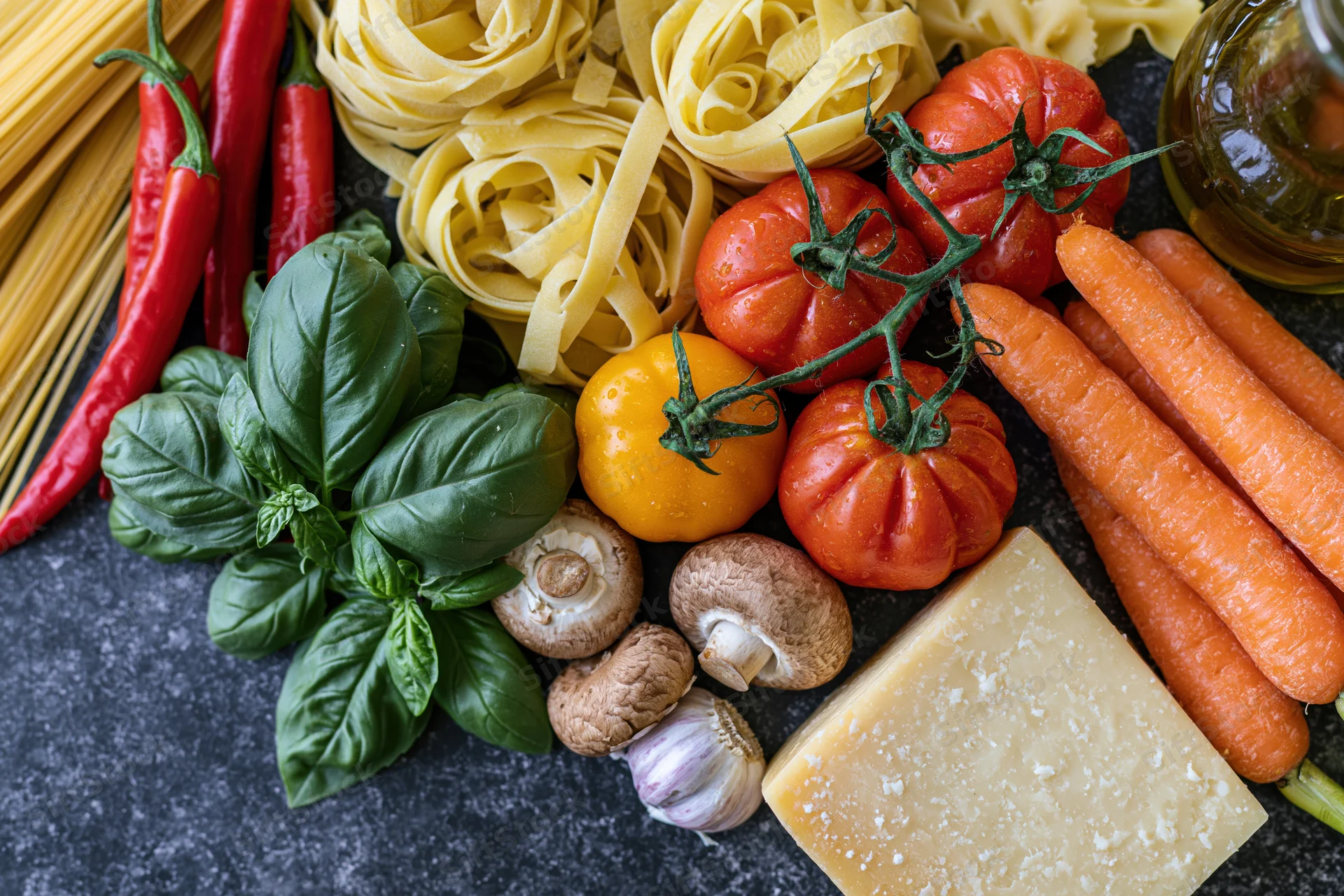 Fresh Italian cooking ingredients arranged on dark surface