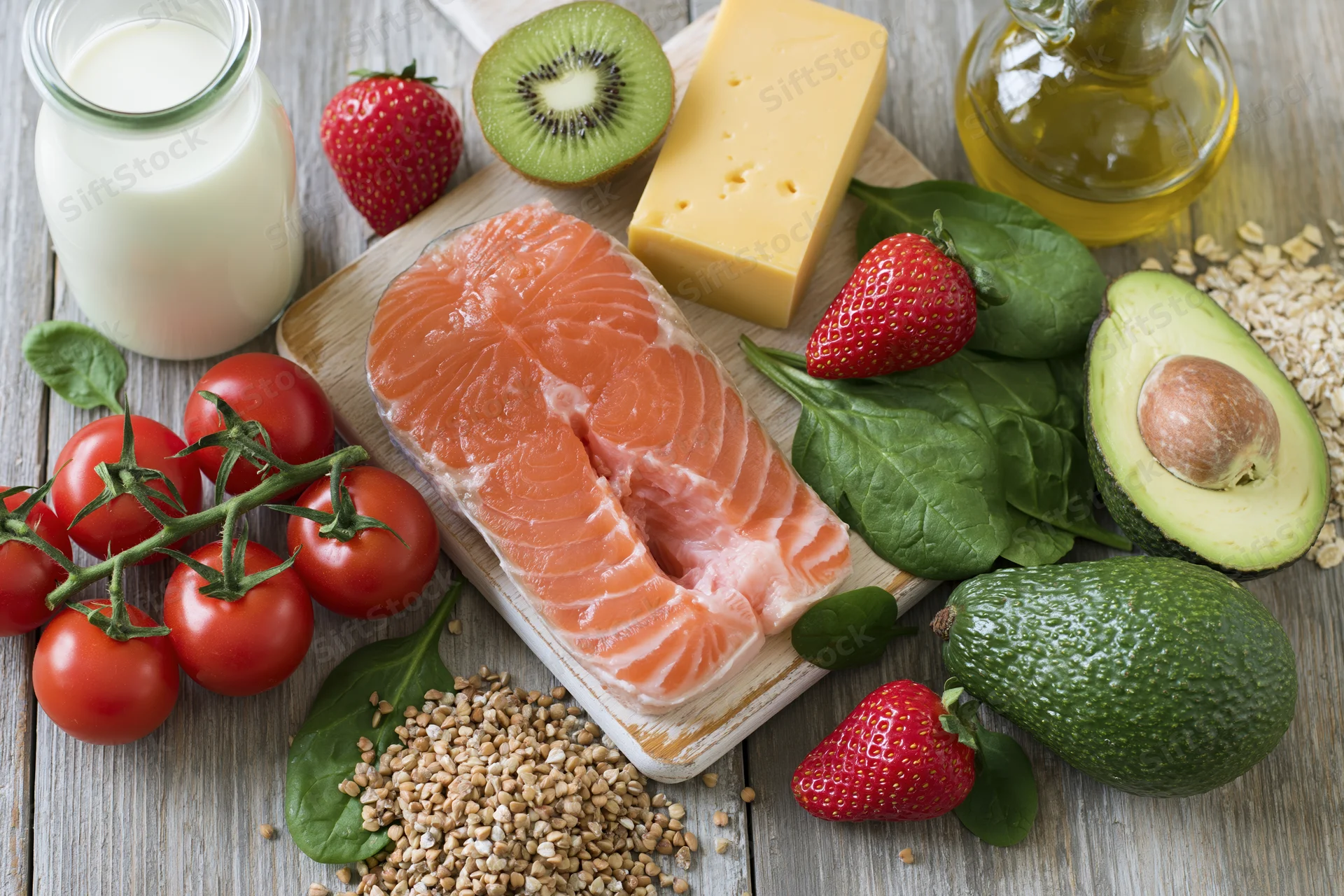 Salmon fillet and assorted fresh produce arranged on wooden surface for balanced diet display