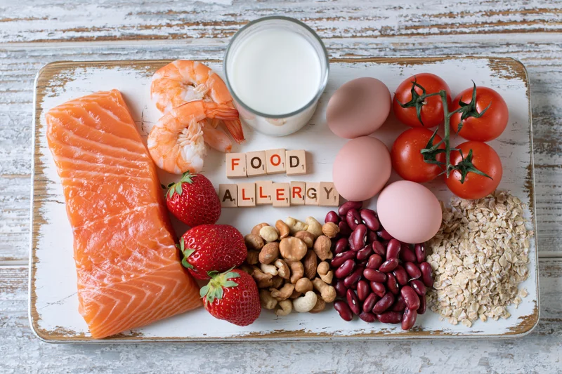 Common food allergens arranged on a distressed wooden tray in a flat lay view