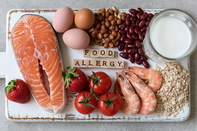 Common food allergens arranged on a distressed white tray with wooden letter blocks spelling allergy
