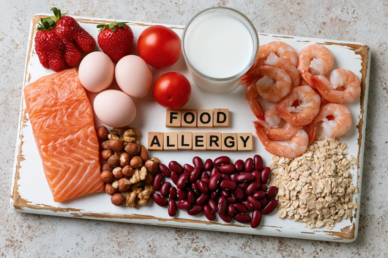 Common food allergens arranged on a distressed white tray with wooden blocks spelling food allergy