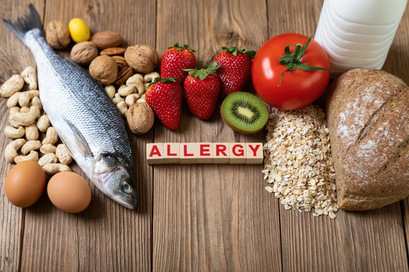 Common food allergens arranged on a rustic wooden surface with wooden blocks spelling allergy