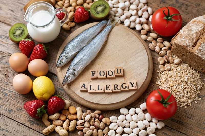 Common food allergens arranged on a wooden surface with wooden blocks spelling food allergy